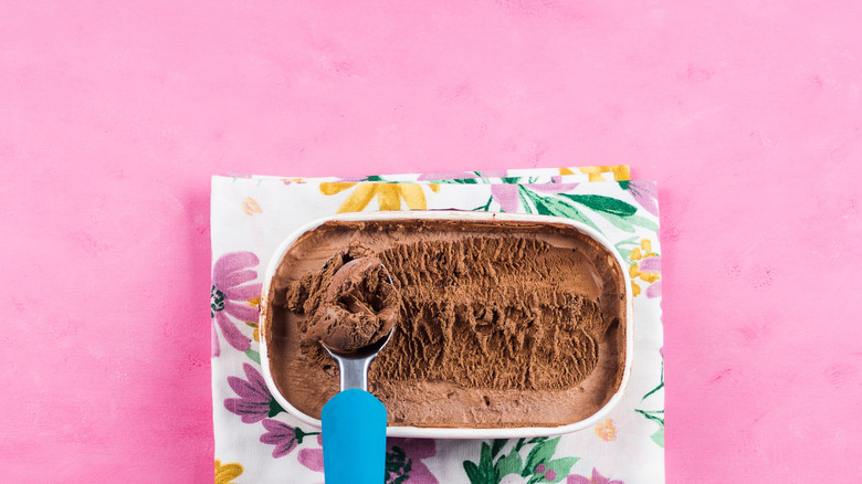chocolate ice cream in rectangular tub on pink table