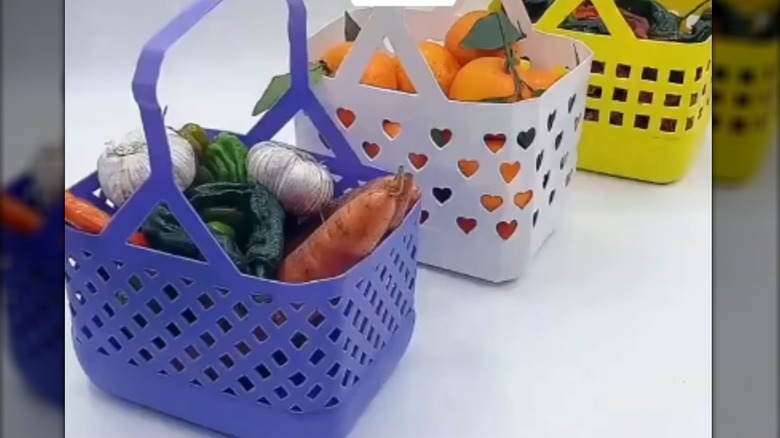 Three colorful baskets made from detergent bottles are filled with produce.