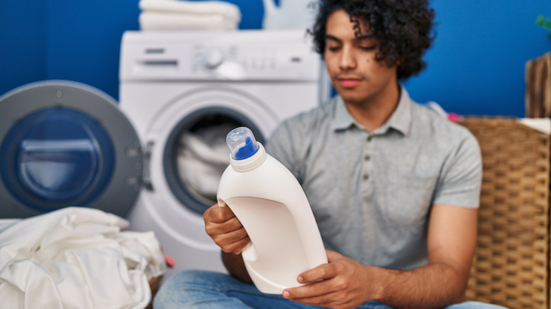 A young biracial person is doing laundry.