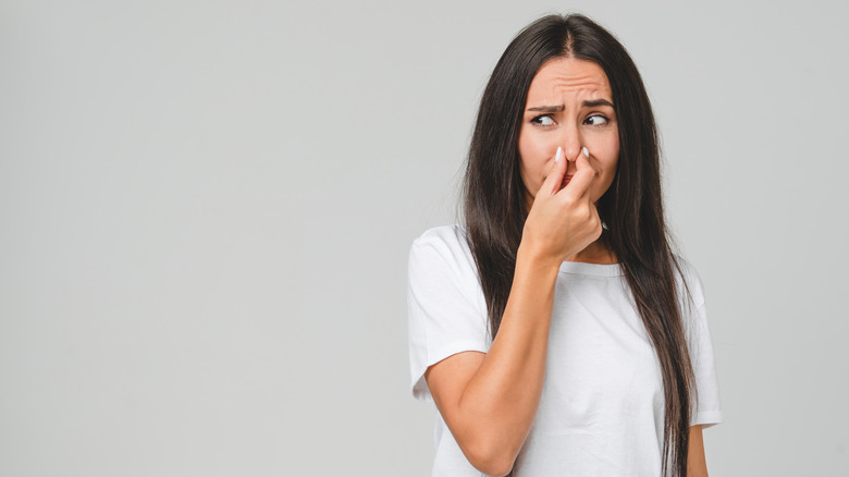 Woman tries to keep from smelling a bad odor.