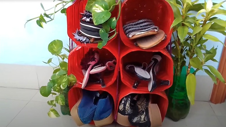 Several pairs of shoes are stored in a rack made from plastic bottles.