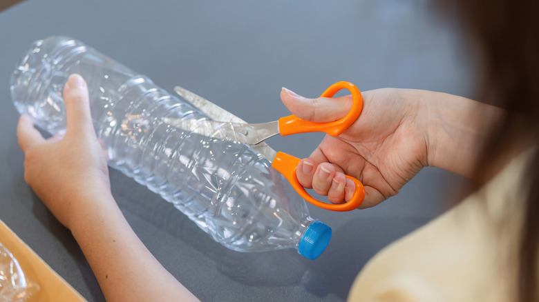 A young woman cuting a plastic bottle with a cutter