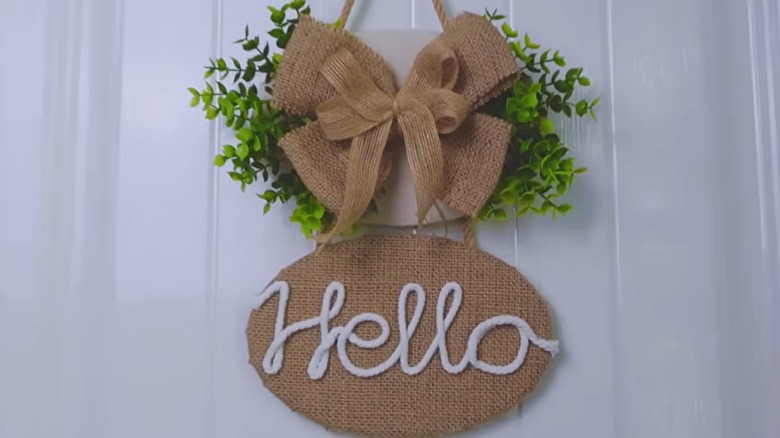 A handmade burlap sign reading "hello" hangs on a door.