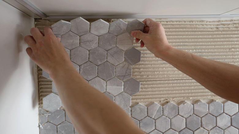 Man laying tiles on wall