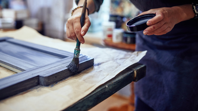 man painting a piece of wood on a table