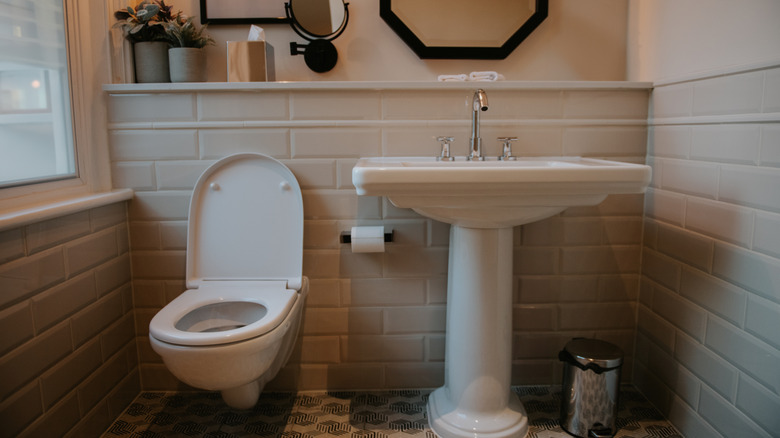 modern bathroom with clean white tile and pedal sink