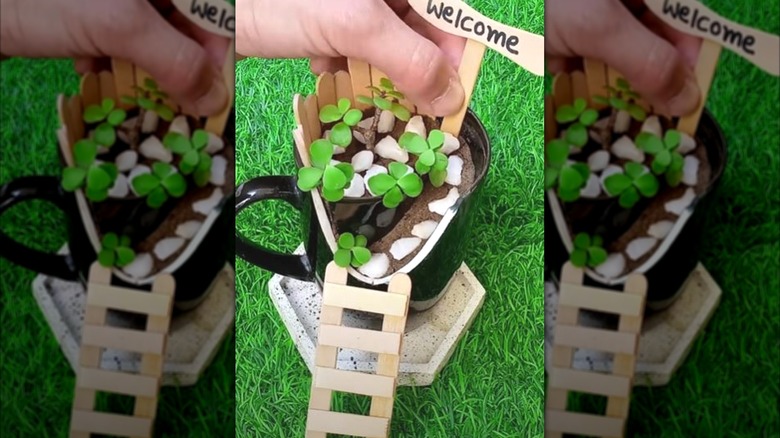 Person creating a fairy garden with a broken mug