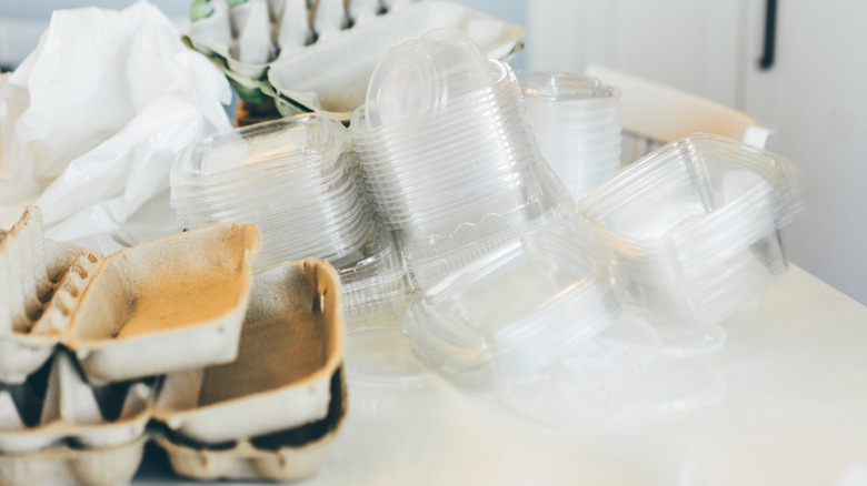 A stack of empty deli containers beside some empty egg cartons