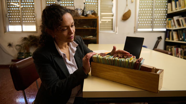 woman organizing paperwork in box at desk