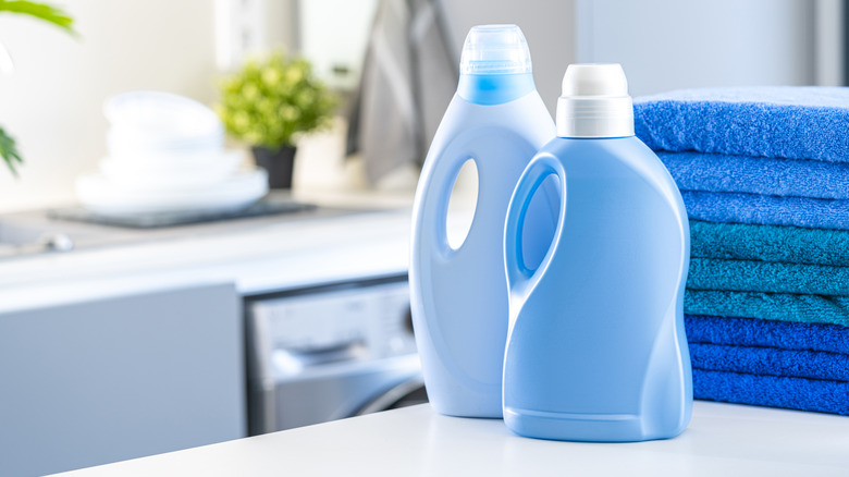 Blue laundry detergent bottles on counter near towels
