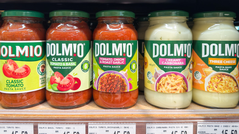 Jars of pasta sauce are arranged on a grocery store shelf.