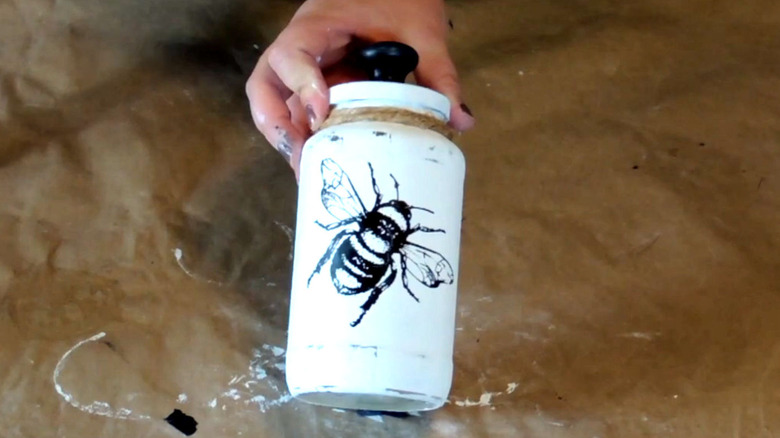 A repurposed pasta jar with a coat of paint and stencil can be used for storage.