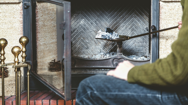 A person scooping ashes out of a fireplace