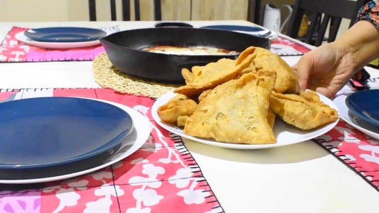 Person putting plate of food on dining table with place settings