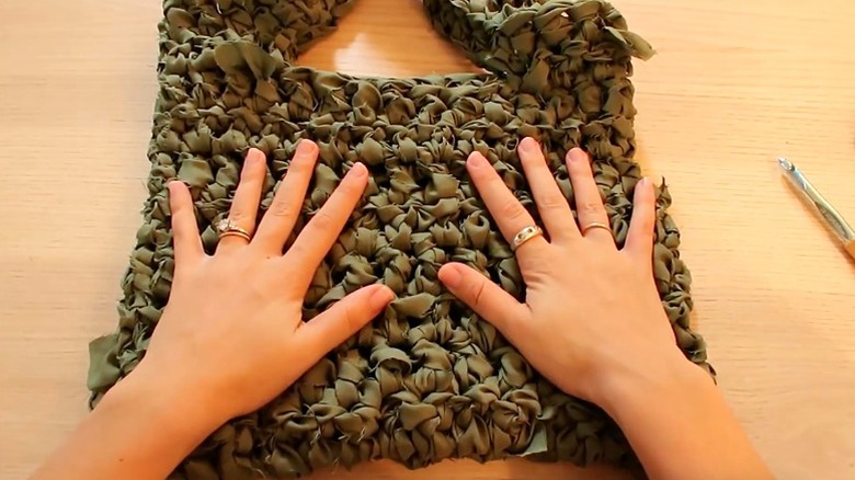 Woman's hands on crocheted tote bag made from bed sheets