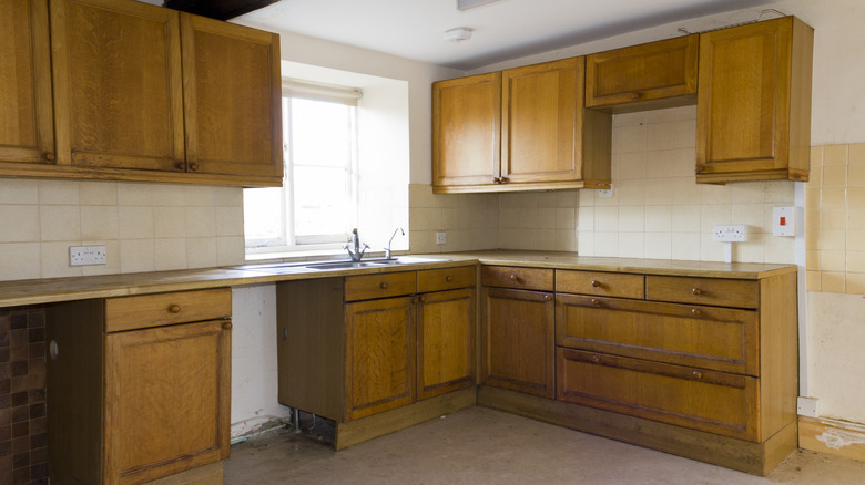 dated kitchen with wooden cabinets in a vacant home