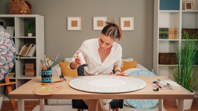 Female artist pouring epoxy resin onto craft
