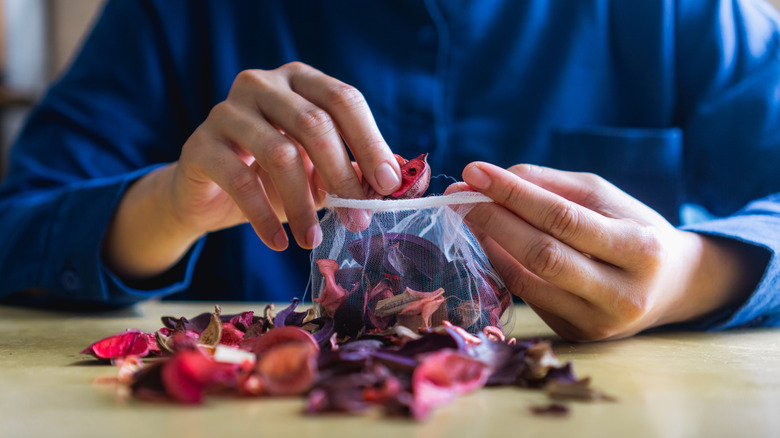 A person fills a mesh sachet will dried flower petals