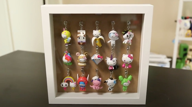 white shadow box on table with Hello Kitty keychains inside