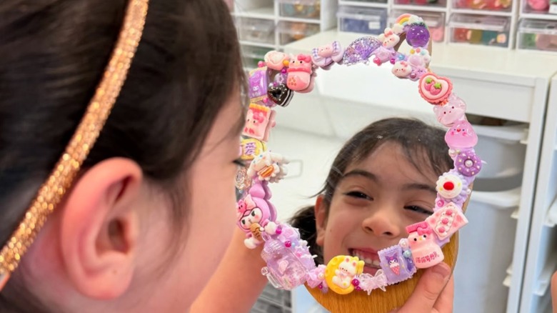 little girl looking into decoden mirror with charms on it