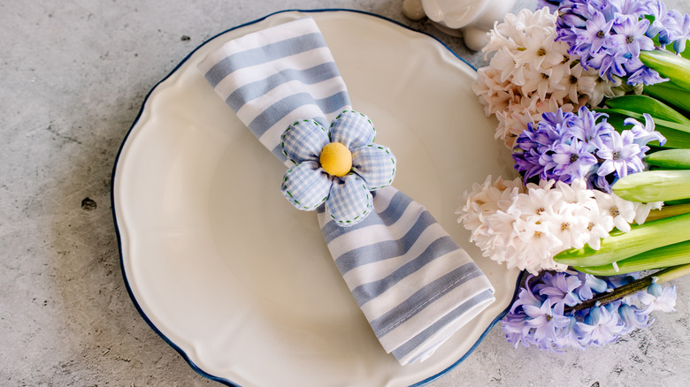 flower charm napkin on blue and white napkin on white plate next to flowers