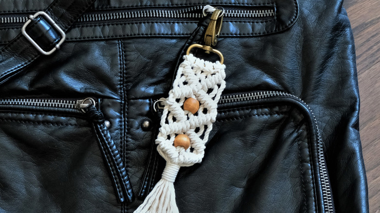 White and bead keychain on black bag with zippers
