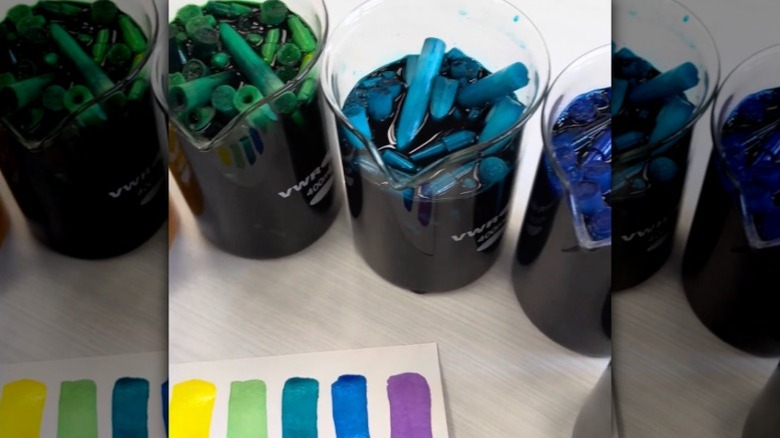 The inside of colored markers soak in glass jugs full of water to create watercolor paints.
