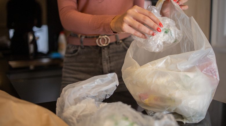 Woman's hand putting a white plastic bag inside another bag