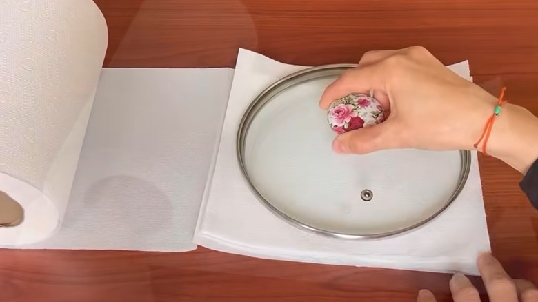 Someone holding pot lid on paper towel.