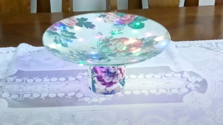 Floral centerpiece made from lid on white tablecloth.