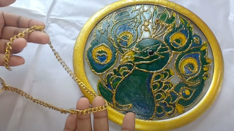 Peacock painted on glass pot lid with gold chain.