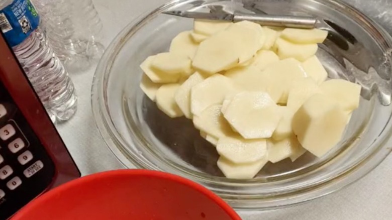 Glass pan lid holding cut potatoes.