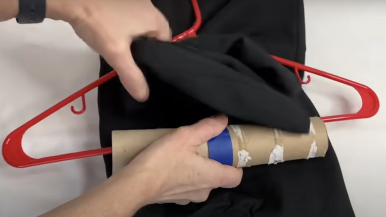 Putting clothes on a hanger with a toilet paper roll.