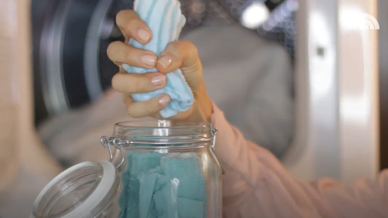 Hand squeezes out a towel made into a dryer sheet