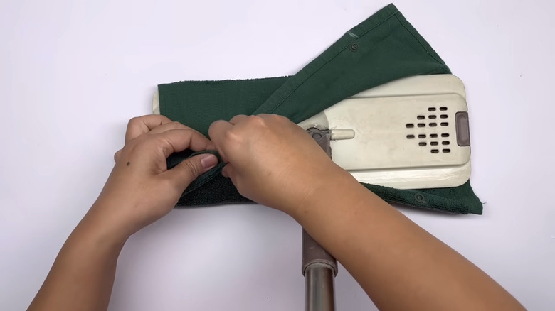 Woman attaching towel made into mopping cloth to her mop