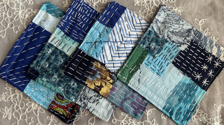 Squares of fabric made into coasters on a lacy background