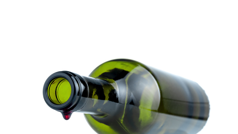 Wine bottle lying down with last drop falling.