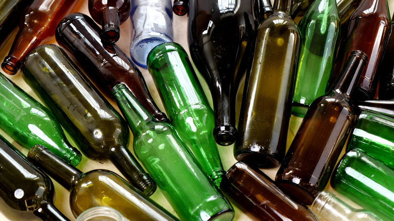 A collection of clean and empty beer and wine bottles in assorted glass colors.