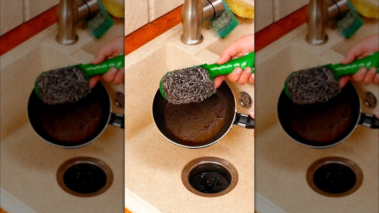 someone holding a steel wool scraper with a green handle in front of frying pan