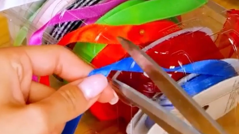 someone cutting a blue ribbon with scissors