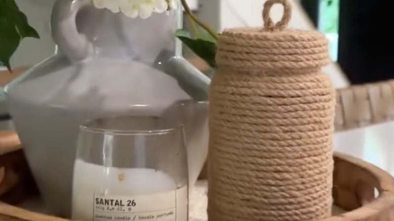 lidded jar with rope next to candle on tray