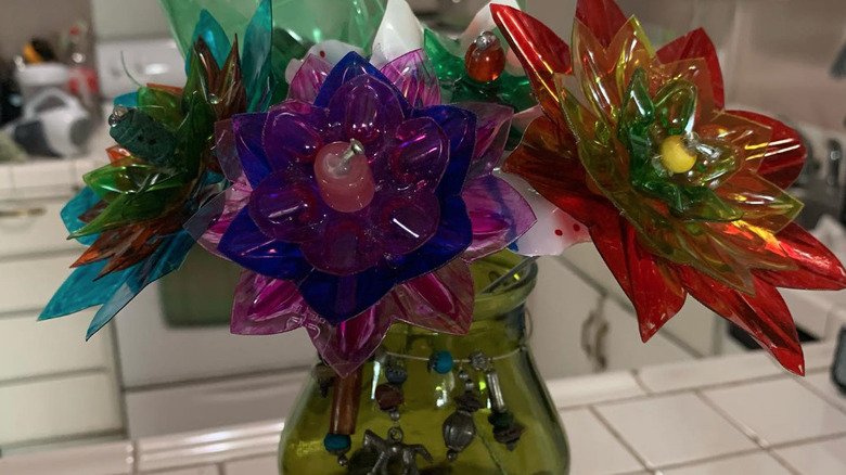 colorful plastic flowers in green vase on counter