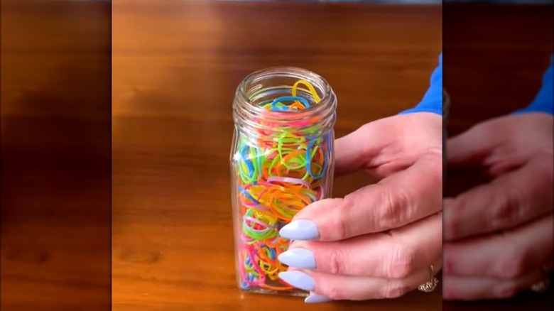 woman holding jar with colorful plastic hair ties