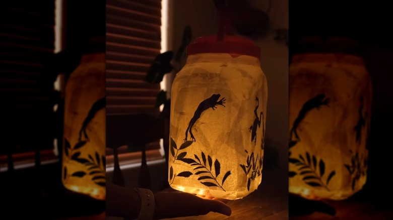 lit lantern with jumping frog and leaves in dark room