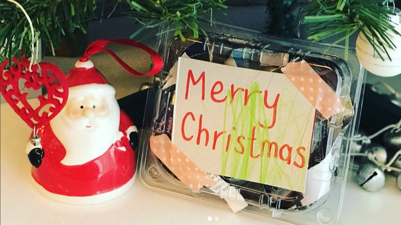 plastic container holding Christmas gift next to Santa decoration