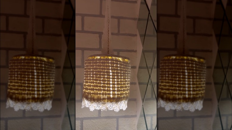 hanging lamp with lace and rope in front of brick wall