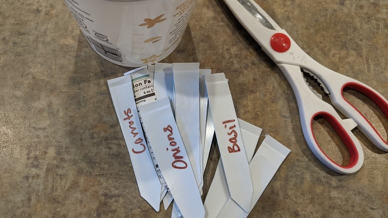 white plant labels made from food container next to scissors