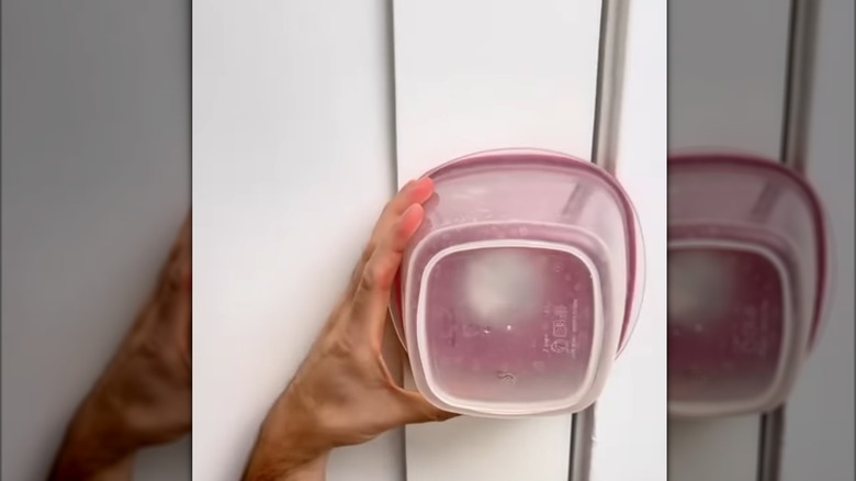 someone holding rubbermaid container on door knob