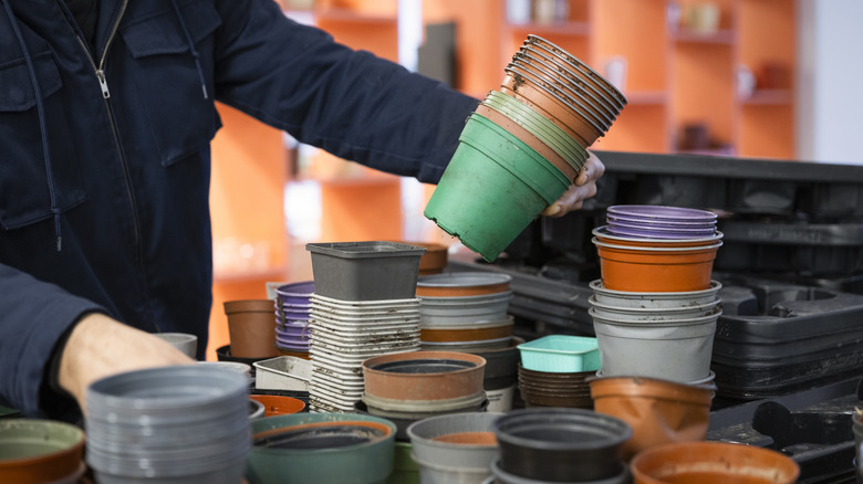 Person in a navy blue jacket investigating multicolored plastic nursery pots.