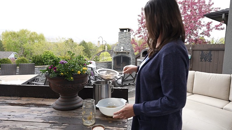 A person straining the potato peel tea to use as a fertilizer